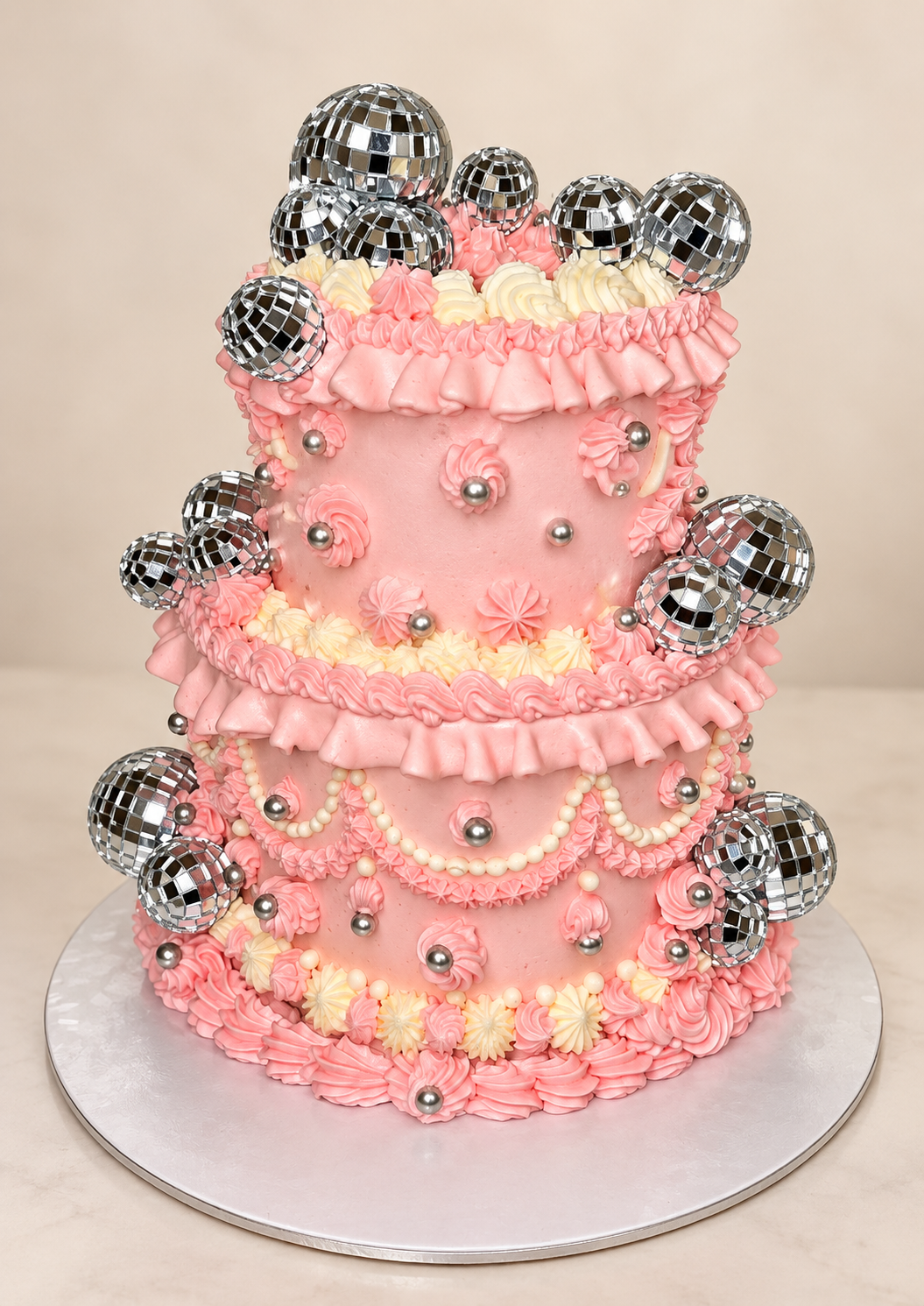 Layer cake rose décoré de boules disco, présenté entier sur son plateau